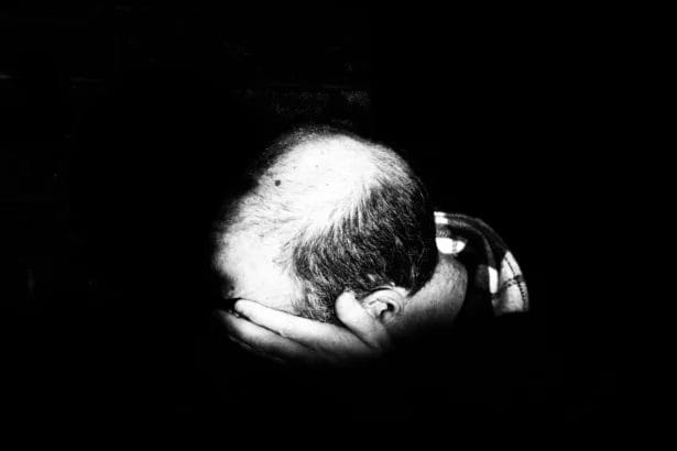 Bald Man With Hands On Head In Black And White Photo