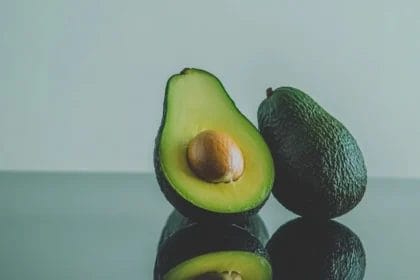 Close-Up Of Halved And Whole Avocados On Reflective Surface