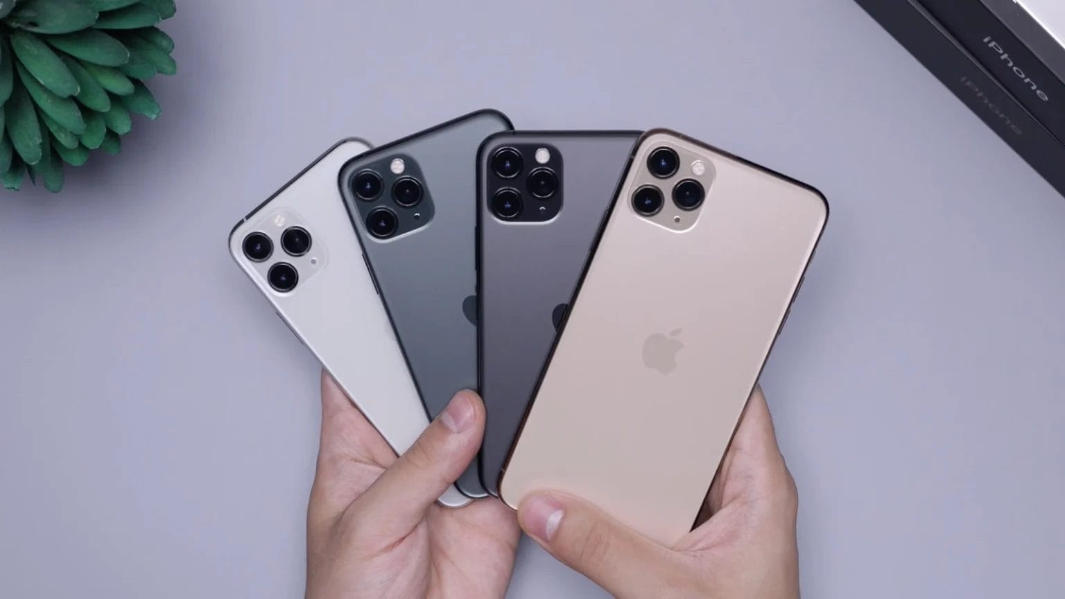 Man Holding Two Space Gray And Two Silver Iphones.