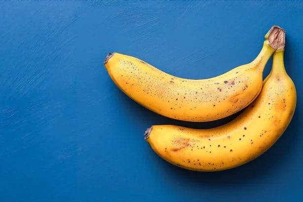 Two Ripe Bananas With Brown Spots On A Blue Background.